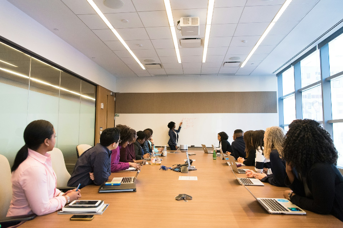 des employés en train de travailler ensemble en regardant une femme indiquant un tableau